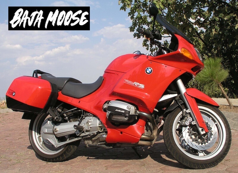 Red BMW R1100RS motorcycle parked in the street with a tree and sky in background