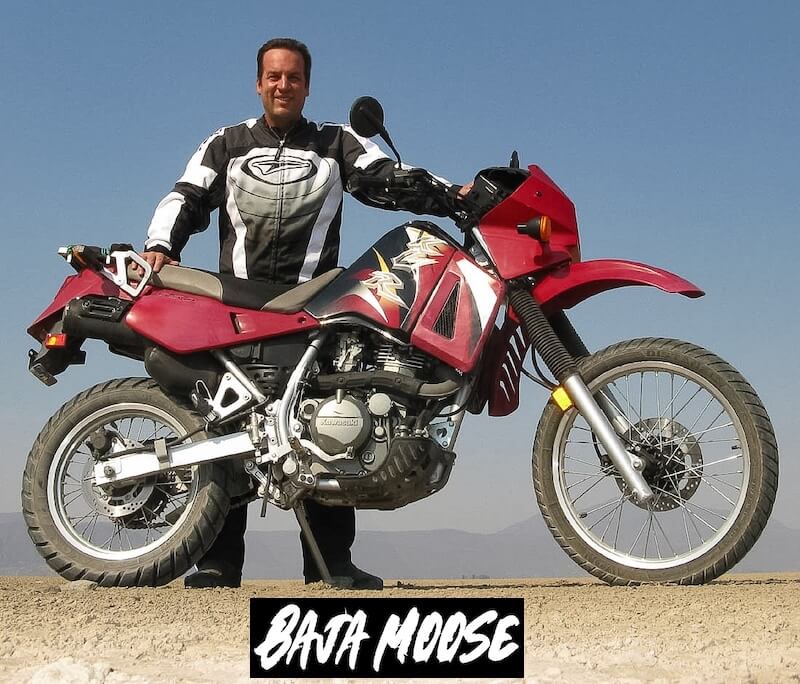 Baja Moose in riding gear standing behind his Kawasaki KLR650 adventure motorcycle